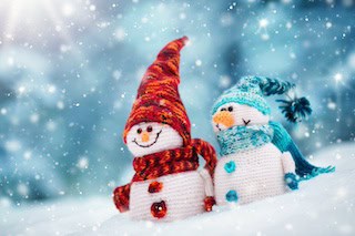 Image of little knitted snowmans on soft snow on blue background